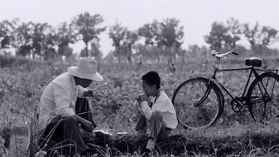 Xiaolei et son père mangent une pastèque dans les champs